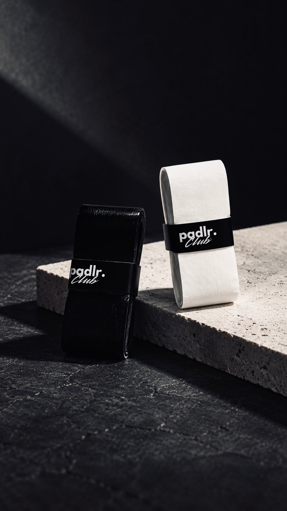 Padlr Club black and white padel overgrips on a stone step, premium non-slip padel and tennis overgrips