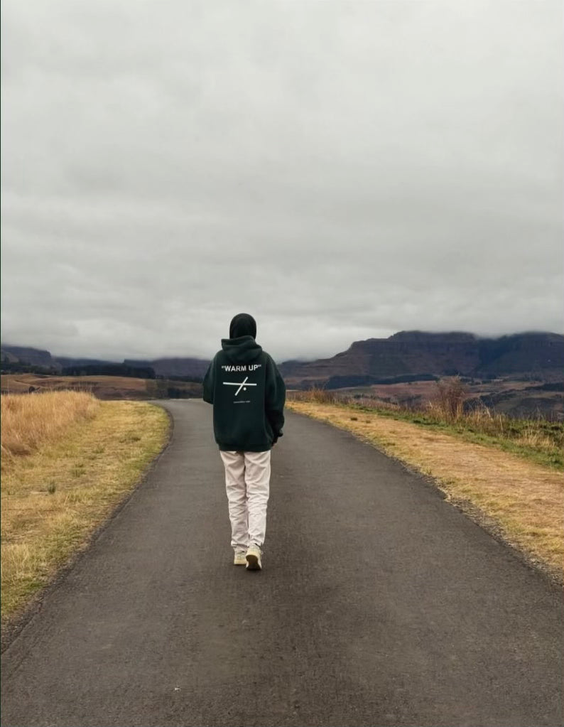 Customer wearing a green Warm Up hoodie on a mountain road